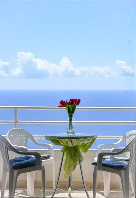 a table with a vase of flowers on a balcony at The rising sun-Stylish Sea View Apartment in Budva