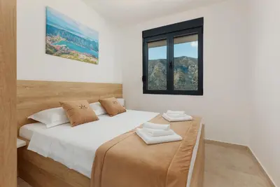 a white bedroom with two beds and a window at DM Apartments in Kotor