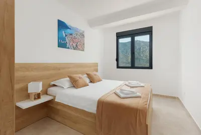 a white bedroom with a bed and a window at DM Apartments in Kotor