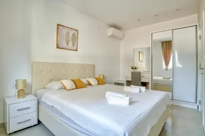 a white bedroom with a large white bed with yellow pillows at The Golden Luxury Apartments in Kotor
