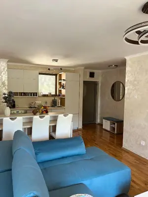 a living room with a blue couch and a kitchen at V Lux Apartment Sveti Stefan in Sveti Stefan