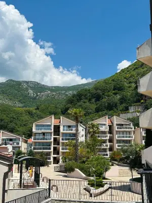 a group of apartment buildings with a mountain in the background at V Lux Apartment Sveti Stefan in Sveti Stefan