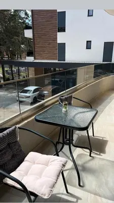a table and chairs on a balcony with a view of a car at Glamur Apartman - Ulcinj in Ulcinj