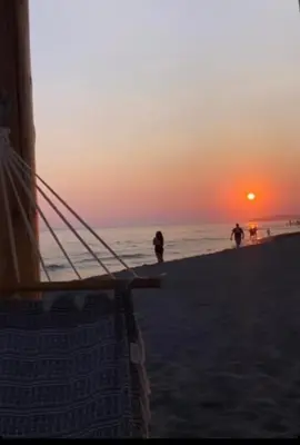 a sunset on the beach with people walking on the beach at Glamur Apartman - Ulcinj in Ulcinj