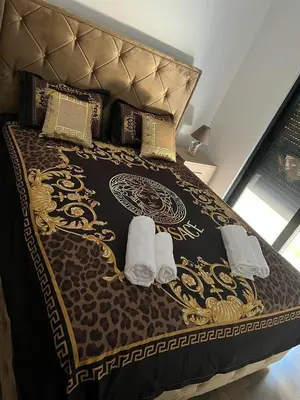 a bed with a brown and gold bedspread and two towels at Glamur Apartman - Ulcinj in Ulcinj