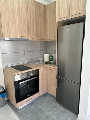 a kitchen with a stainless steel refrigerator and wooden cabinets at Eastside studio in Podgorica