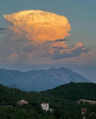 a cloud formation over a mountain range with trees at Lapčiči View in Budva