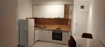 a kitchen with white cabinets and a refrigerator at Biser Apartmani in Podgorica
