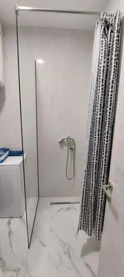 a white bathroom with a shower with a marble floor at Biser Apartmani in Podgorica