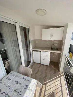 a small kitchen with white cabinets and a table at Apartmani Resetar in Sutomore
