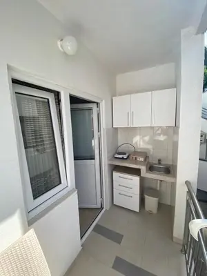 a small kitchen with white cabinets and a window at Apartmani Resetar in Sutomore