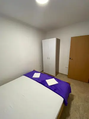 a bedroom with a bed with purple sheets and a cabinet at Apartmani Resetar in Sutomore
