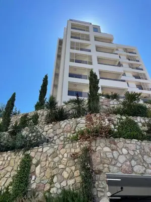 a building with a stone wall in front of a building at Golden Details Apartment in Rafailovici