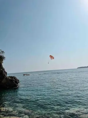 a person is flying a kite over the water at Golden Details Apartment in Rafailovici
