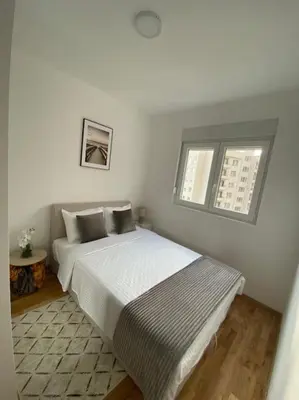 a white bedroom with a bed and two windows at Apartment Olivia in Becici