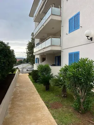 a white building with blue windows and a walkway at Seaside Apartment in Becici in Budva