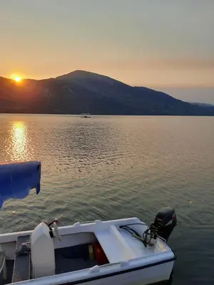 a boat in the water with the sunset in the background at Honey Home in Podgorica