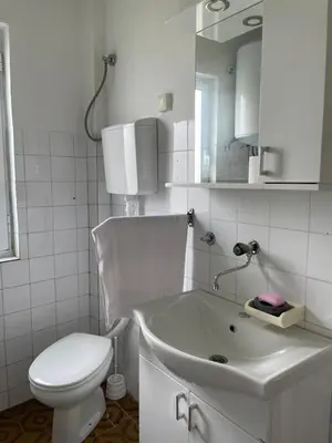 a white bathroom with a toilet and a sink at Honey Home in Podgorica