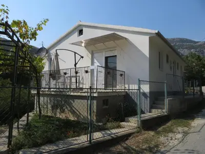a white house with a fence in front of it at Apartmani Stanislav in Petrovac na Moru