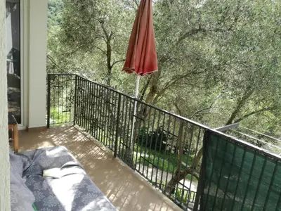 a patio with an umbrella and a bench on a balcony at Apartmani Stanislav in Petrovac na Moru