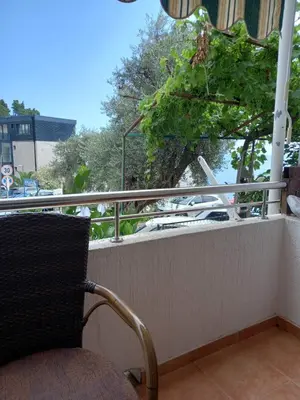 a chair on a balcony with a view of a boat at Apartman Maja in Sveti Stefan