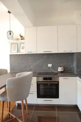 a kitchen with white cabinets and a table and chairs at Status-M Apartments 112 in Becici