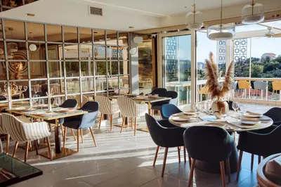 a restaurant with tables and chairs and large windows at Status-M Apartments 112 in Becici