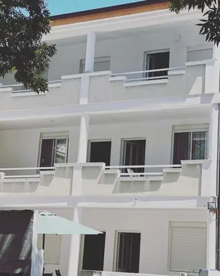 a white apartment building with balconies and an umbrella at Babulje in Ulcinj