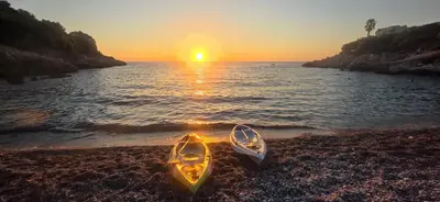 two canoes sitting on a beach with the sunset at MarBis Apartmani near the sea in Utjeha