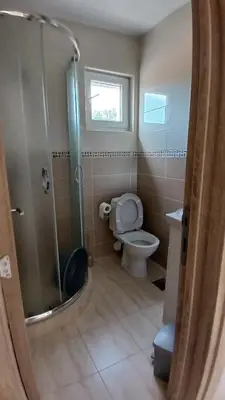 a bathroom with a shower and a toilet and a window at MarBis Apartmani near the sea in Utjeha