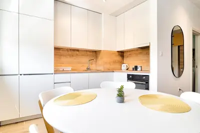 a white kitchen with a white table and chairs at The Riverscape in Podgorica