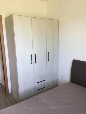 a white cabinet in the corner of a bedroom at M&A Montenegro Apartmani in Golubovci