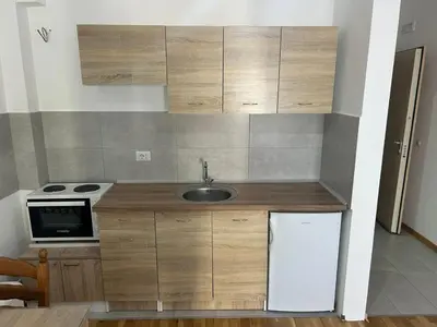a small kitchen with wooden cabinets and a sink at Smakovic Apartments in Ulcinj