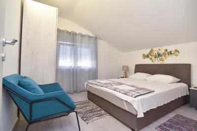 a bedroom with a bed and a blue chair at Apartman 3 in Budva