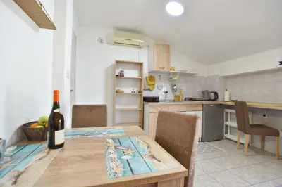 a kitchen with a wooden table and a bottle of wine at Apartman 3 in Budva