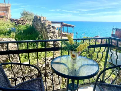 a glass table with a vase of flowers on a balcony at Apartments Zuto in Ulcinj