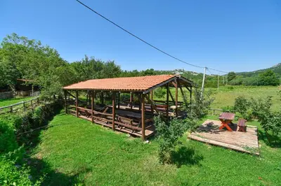 a wooden gazebo with a roof in a field at Holiday Home Dapcevic in Budva