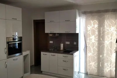a kitchen with white cabinets and a stove top oven at Студия для отдыха или проживания in Dobra Voda