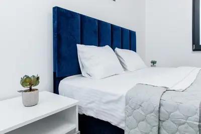 a bedroom with a large bed with a blue headboard at Lira Suites in Donji Štoj