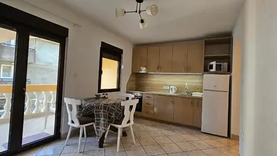 a kitchen with a table and chairs and a refrigerator at Apartmani Lime in Petrovac na Moru