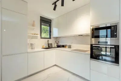 a white kitchen with white cabinets and a microwave at Lux Grand Apartment Kotor in Kotor