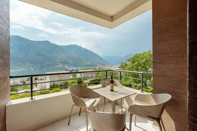 a balcony with a table and chairs and mountains at Lux Grand Apartment Kotor in Kotor