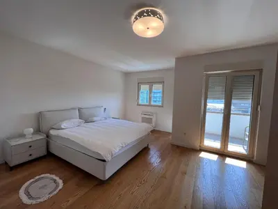 a white bedroom with a bed and a large window at White Homes 37 • Central Point in Podgorica