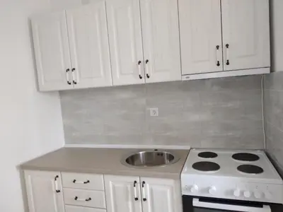 a kitchen with white cabinets and a stove and a sink at Boggi Apartments in Ulcinj