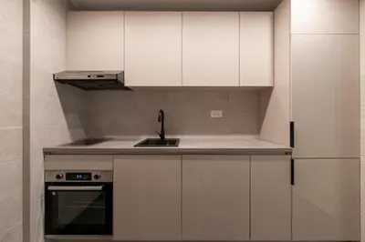 a kitchen with white cabinets and a sink at Soho Suites in Bar