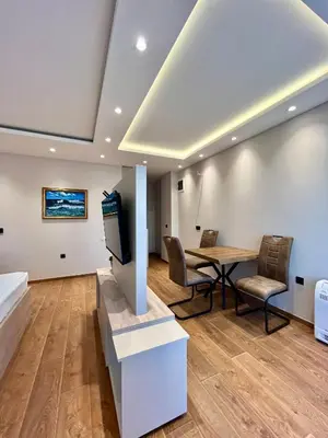 a room with a table and chairs and a television at Perla apartmani in Petrovac na Moru