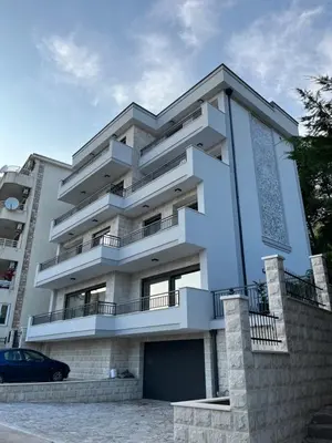 a building with a car parked in front of it at Perla apartmani in Petrovac na Moru