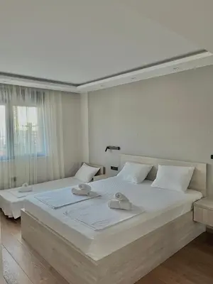 a white bedroom with two beds and a window at Perla apartmani in Petrovac na Moru