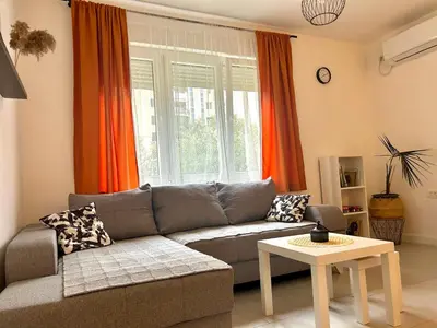 a living room with a gray couch and orange curtains at Cozy apartment, 10 minutes walking distance from the Old Town in Kotor