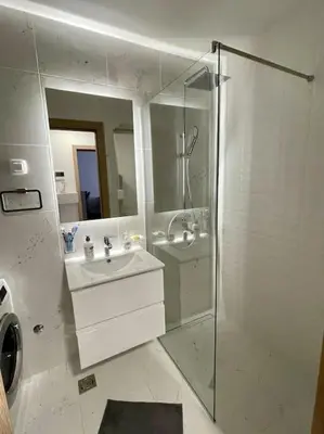 a bathroom with a shower and a sink and a mirror at StayPoint Apartment in Podgorica